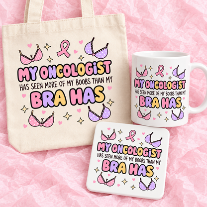 Matching breast cancer awareness gift set with 11oz mug, square ceramic coaster and tote bag on pink tissue paper.