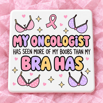 Square 10x10cm ceramic breast cancer awareness coaster with survivor design on pink tissue paper.